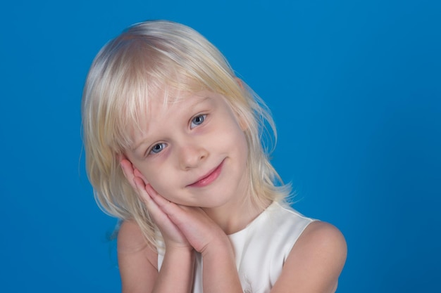 Petite fille aux cheveux blonds tenir la main au visage.