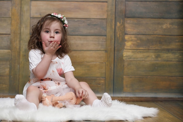 Petite fille aux cheveux bouclés, s'amusant en posant devant la caméra