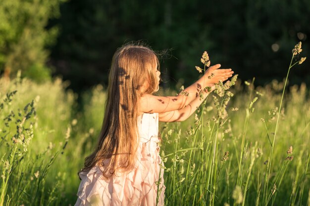 petite fille aux cheveux longs dans une belle robe sur la nature en été