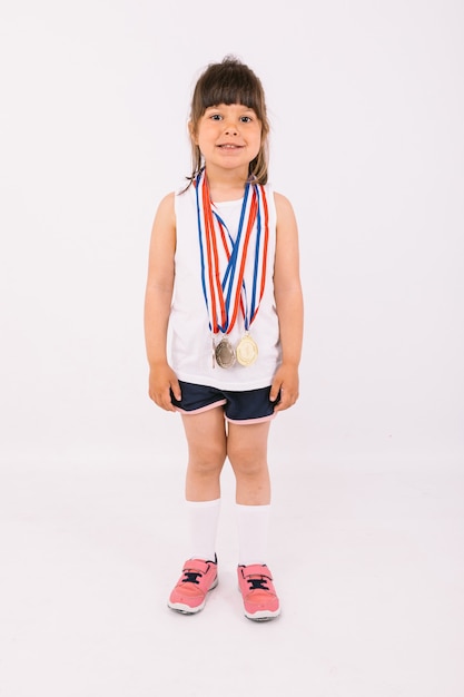 Petite fille aux cheveux noirs avec des médailles de champion de sport. Concept de sport et de victoire