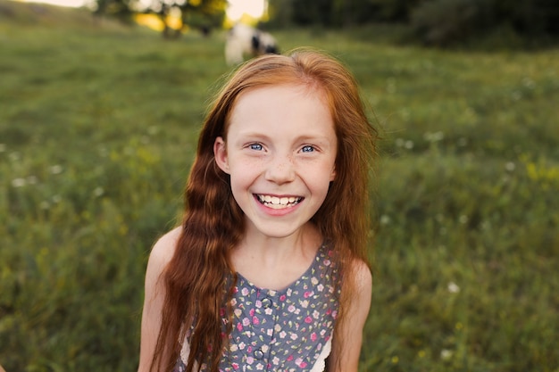 Une petite fille aux cheveux rouge vif sourit largement. Fermer.