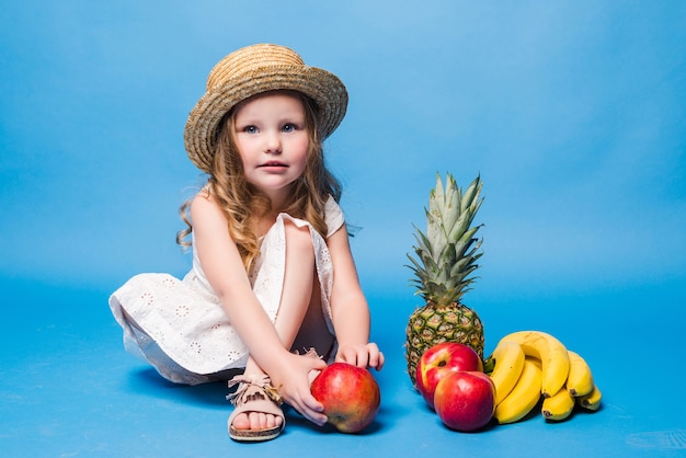 Petite fille aux fruits isolé sur mur bleu