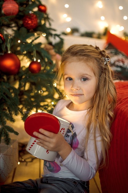 Une petite fille aux longs cheveux blonds a ouvert un cadeau de Noël