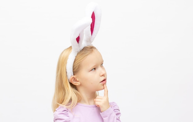 La petite fille aux oreilles roses lapin sur fond blanc.