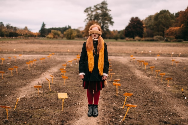 Petite Fille Aux Yeux Bandés Dans L'élégant Vieux Vêtements Façonnés Debout Dans Le Champ Automne Avec Paysage Sombre