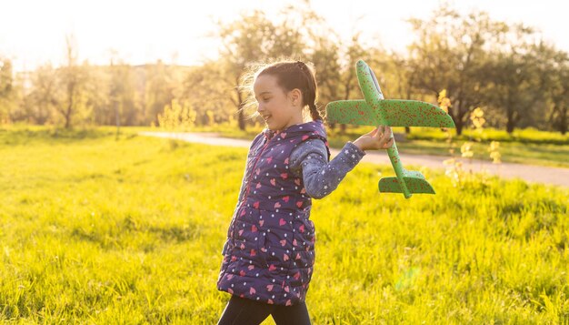 petite fille avec un avion jouet dans les mains en plein air, vis à vent du moteur en caoutchouc.