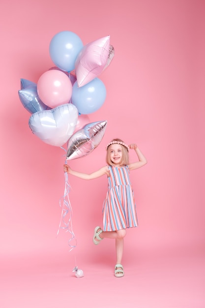 Petite fille avec des ballons sur une surface rose