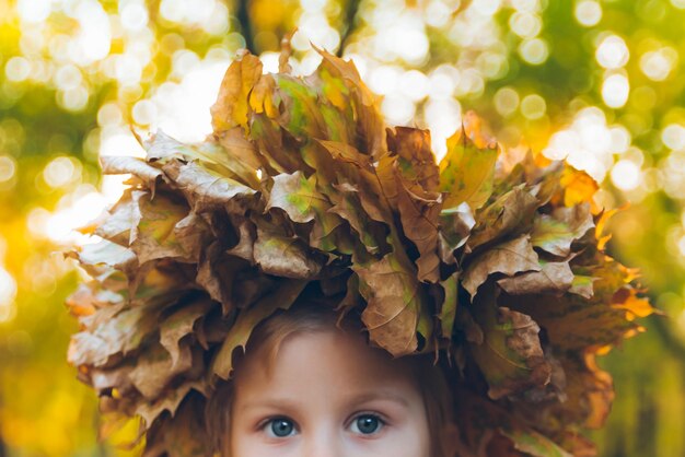 Petite fille en bas âge jouant avec une couronne de feuilles d'érable