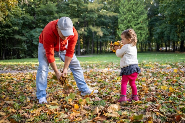 petite fille en bas âge joue avec son père à l'extérieur dans le parc en automne..