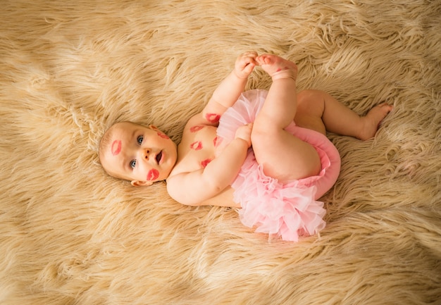 Une petite fille avec beaucoup de baisers rouges sur son corps et sa culotte rose est allongée sur une couverture beige moelleuse