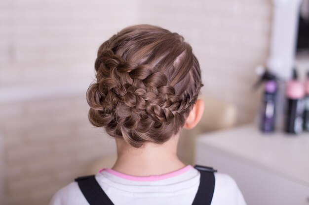 Petite fille avec une belle coiffure sur fond de salon de coiffure