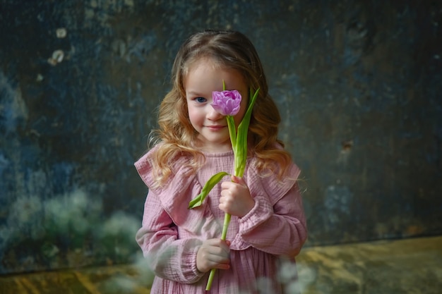 Une petite fille belle dans une robe rose avec des tulipes lilas