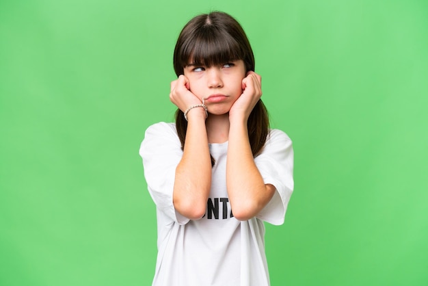 Petite fille bénévole sur fond isolé frustré et couvrant les oreilles