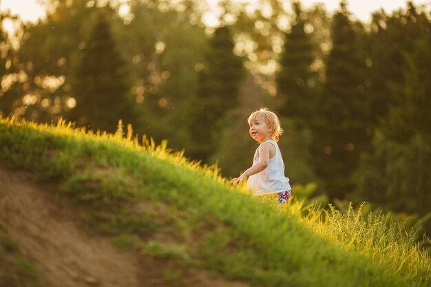 Petite fille blonde de 2-3 ans jouant dans le parc d'été et sentant les fleurs. Concept d'activité enfants