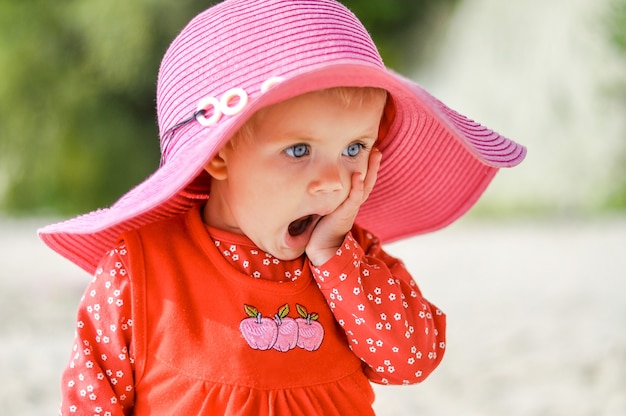 Petite Fille Blonde Au Chapeau Sur La Plage Dans Une Robe Rouge Au Printemps