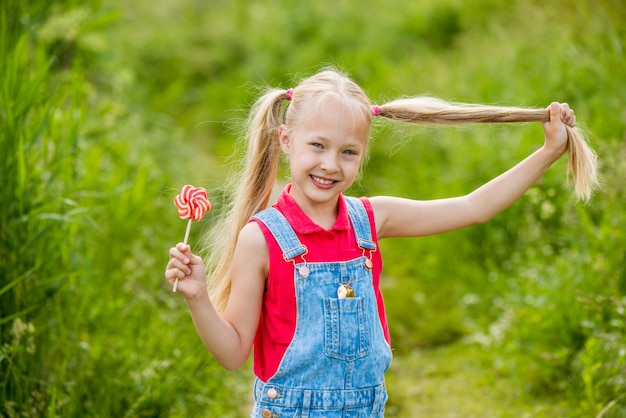 Petite fille blonde aux cheveux longs et un bonbon