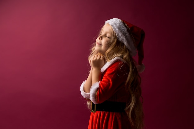 petite fille blonde dans un costume de père Noël fait un vœu