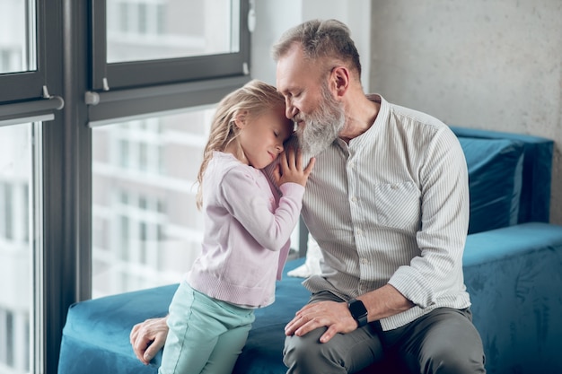 Une petite fille blonde debout près de son père