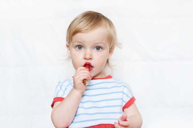 Petite fille blonde drôle maquillage lèvres avec rouge à lèvres de maman. Apprendre à être une femme.