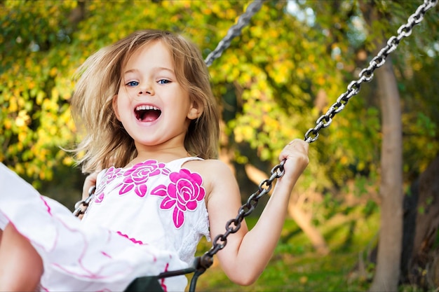 Petite fille blonde enfant s'amusant sur une balançoire