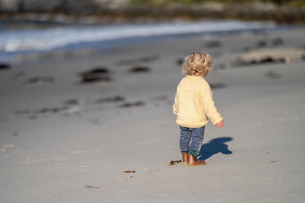 Une petite fille blonde explore le sable de la plage en Australie.