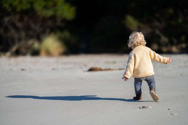 Une petite fille blonde explore le sable de la plage en Australie.