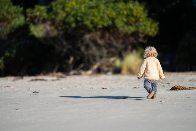 Une petite fille blonde explore le sable de la plage en Australie.