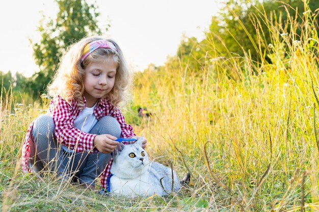 Une petite fille blonde marchant un chat de race blanche en laisse