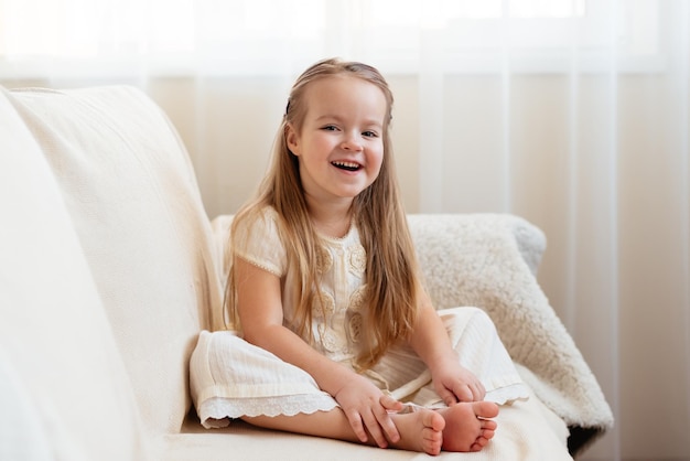 Petite fille blonde mignonne assise sur un canapé