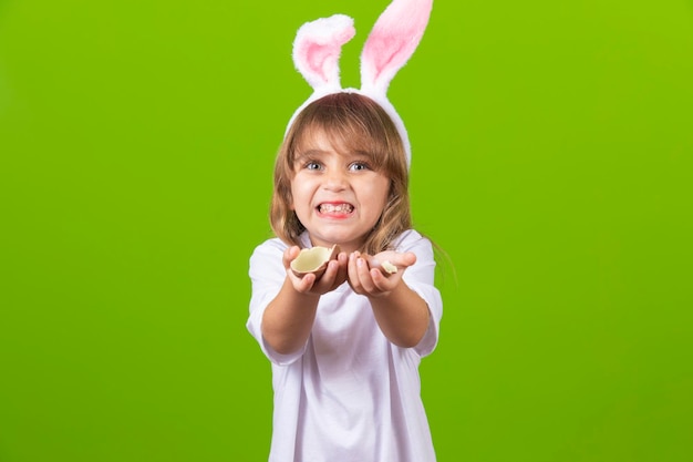 Petite fille blonde avec des oreilles de lapin en chocolat sales mangeant des oeufs de Pâques