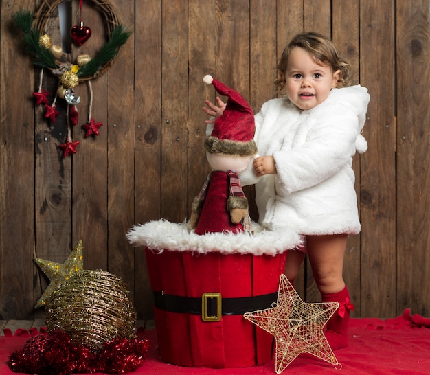 Petite fille blonde porte un manteau blanc sur bois