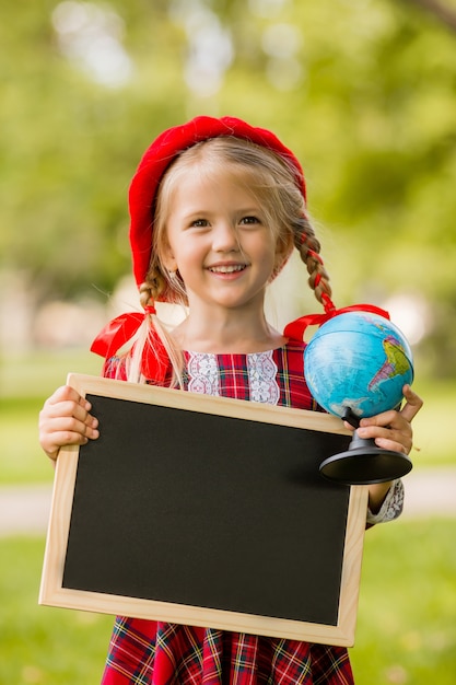 petite fille blonde première niveleuse en robe rouge et béret tenant un dessin vide et globe