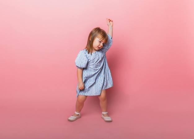 Petite fille blonde en robe bleue sur fond rose Mode décontractée élégante et confortable pour les enfants