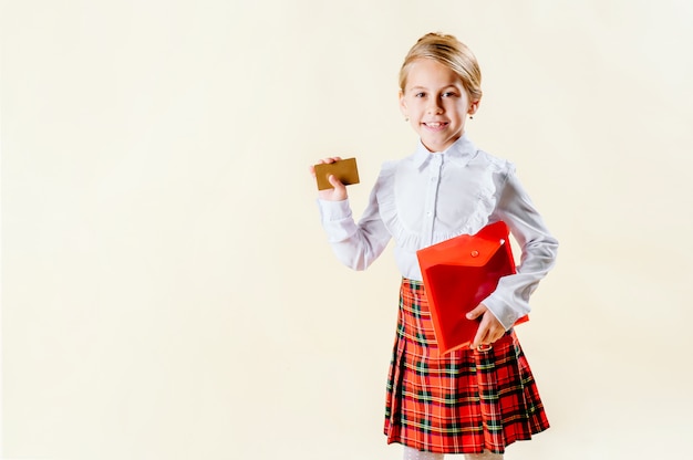 Petite fille blonde tenant une carte vierge en uniforme scolaire