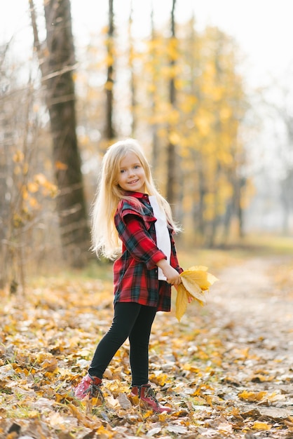 Petite fille blonde tenant des feuilles d'automne