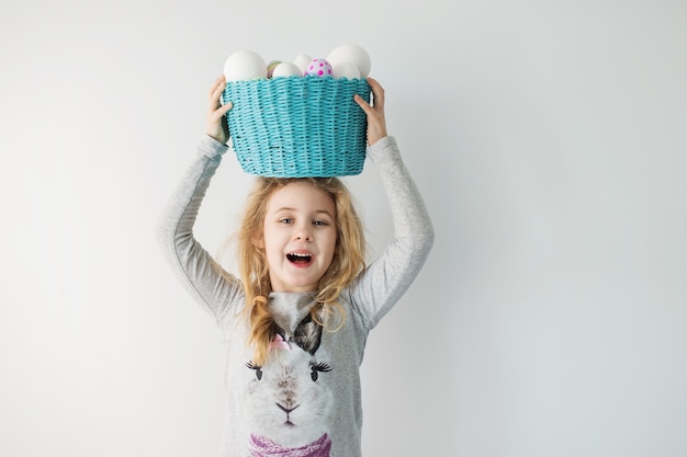 Petite fille blonde tenant un panier avec des œufs peints. Jour de Pâques.