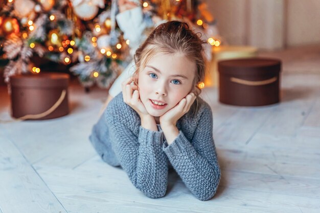 Petite fille avec boîte-cadeau près de l'arbre de Noël à la maison
