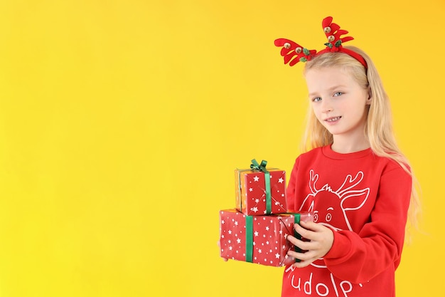 Petite fille avec des boîtes de Noël sur fond jaune