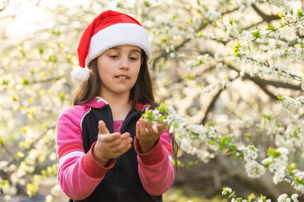 Petite fille en bonnet de noel jouant dans le jardin