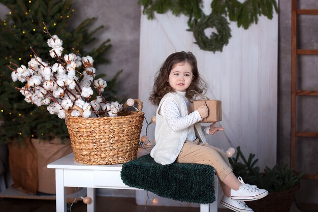 Petite fille bouclée ouvre un cadeau à Noël.