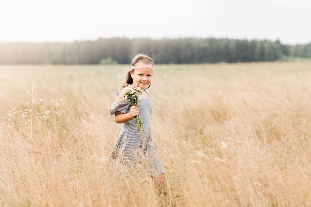 Photo une petite fille avec un bouquet de fleurs marche dans le pré. amour et floraison printanière