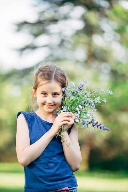 Photo petite fille avec un bouquet de fleurs sauvages.