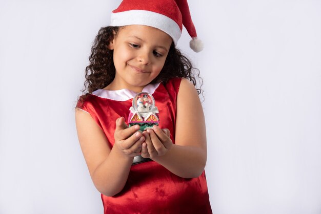 Petite Fille Brésilienne Habillée Avec Un Costume De Noël Tenant Une Boule à Neige