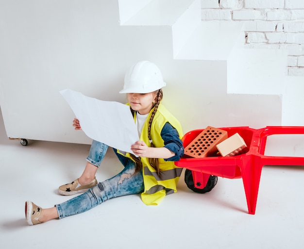 Petite fille avec brouette sur fond blanc. Construction