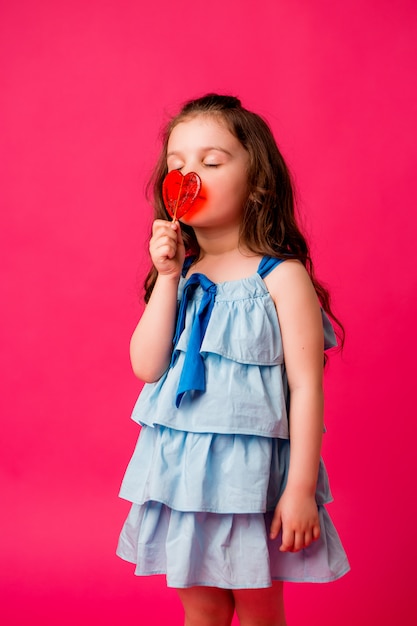 petite fille brune sur fond rose souriant