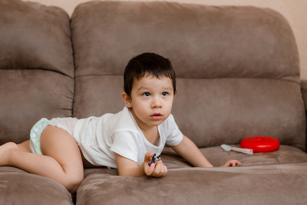 Une petite fille brune joue à la maison sur le canapé