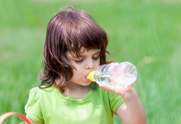 Petite fille buvant de l'eau d'une bouteille