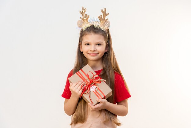 Une petite fille avec un cadeau de Noël sur fond blanc isolé.