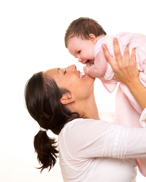 Petite fille câlin dans les bras de la mère jouant au heureux