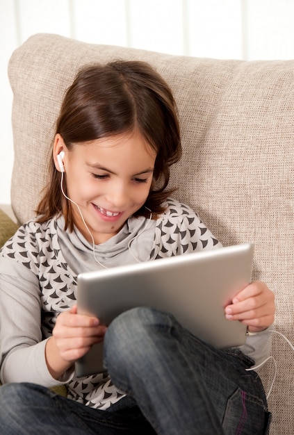 petite fille sur le canapé avec tablette tactile